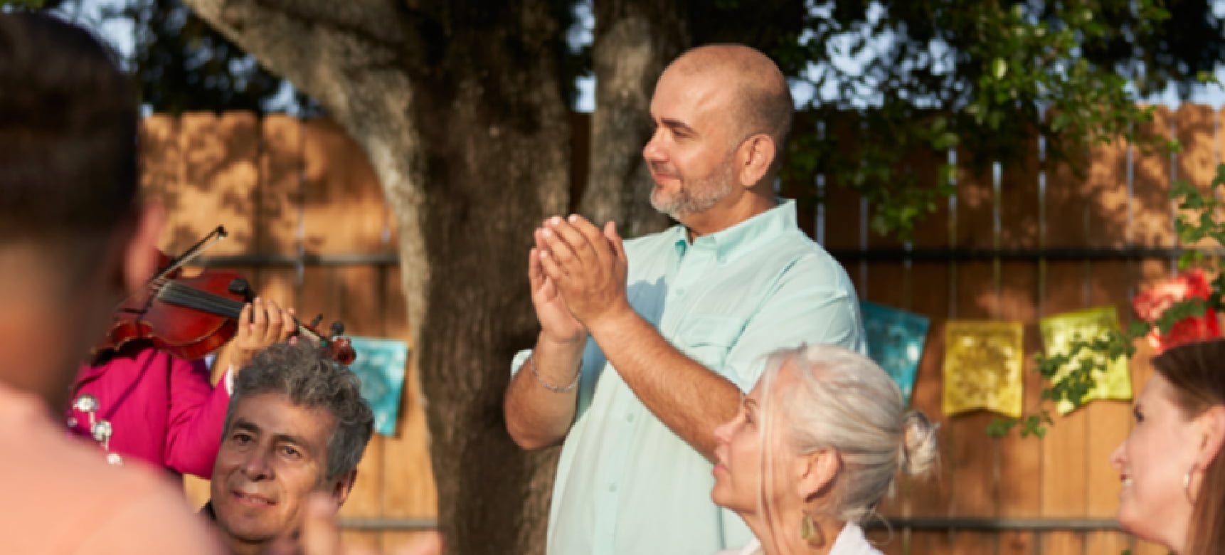 Hombre aplaudiendo en una reunión grupal al aire  libre.